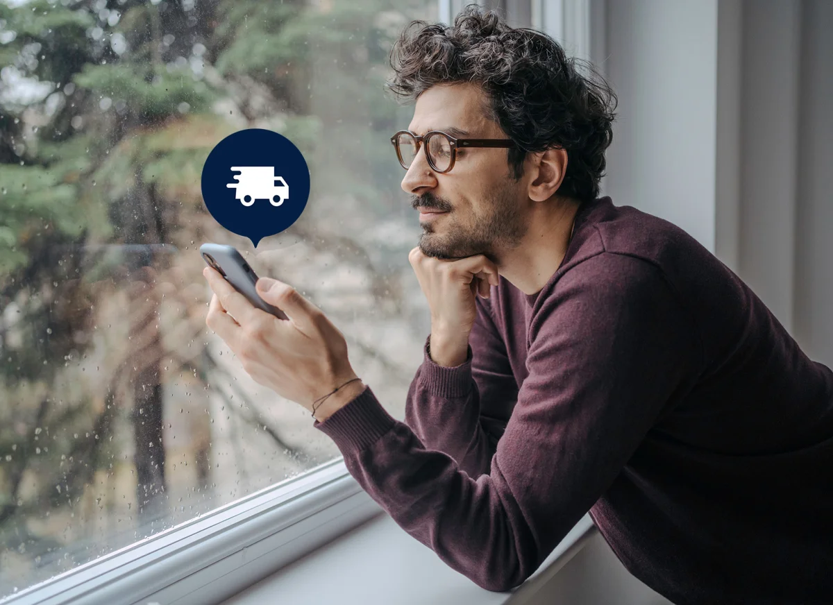 Man at window receives delivery notification on smartphone